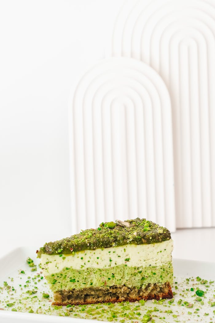 Delicious pistachio slice with textured layers served on a white plate, perfect for dessert lovers.